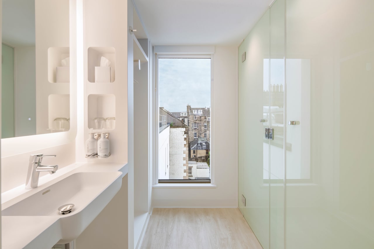Working closely alongside YOTEL at the design stage of the project, Roca created a bathroom solution that closely aligned with the brand standards. This included the Gap wall‐hung WC and a bespoke vanity unit, in addition to bespoke washroom countertops for the public areas of the hotel. The bespoke units were made using Surfex®, a malleable solid surface material formulated from a combination of minerals and resins. The unique properties of Surfex allow it to be poured into a production mould, enabling complex designs with no joints or seams. The materials properties also permit ‘on-­‐site’ changes to the finished product, catering to different guestroom sizes and configurations. At YOTEL Edinburgh the advantages of Surfex were harnessed to create a wash basin bowl with an integrated unit that maximises countertop space, providing ample storage space for toiletries and grooming products.1